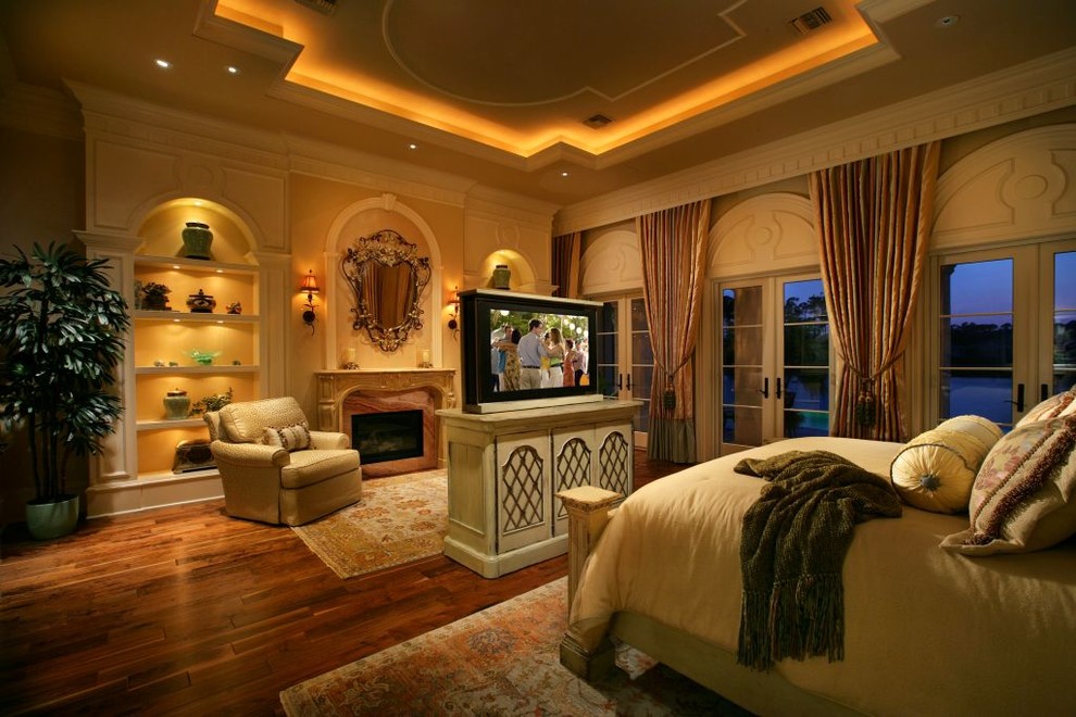 Mediterranes Schlafzimmer mit gelber Wandfarbe, braunem Holzboden und Kamin in Miami