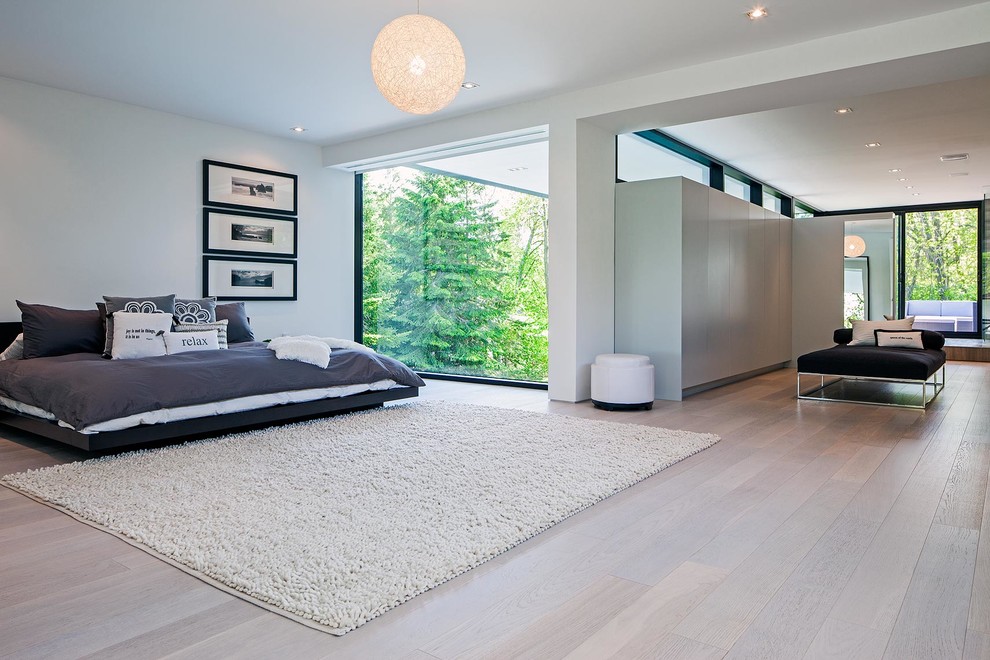 Inspiration for a large modern master bedroom in Toronto with white walls and light hardwood flooring.