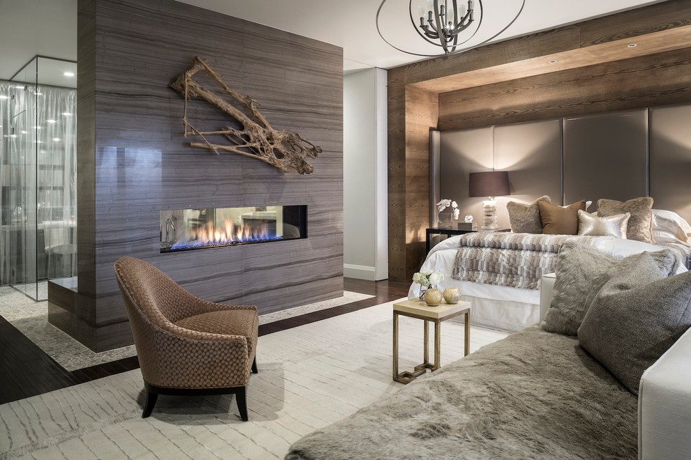 Inspiration for a contemporary master and grey and silver bedroom in Other with dark hardwood flooring, a two-sided fireplace, a tiled fireplace surround and feature lighting.