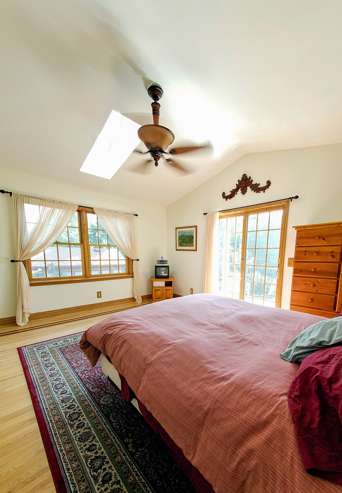 Diseño de dormitorio principal tradicional renovado de tamaño medio sin chimenea con paredes blancas, suelo de madera clara y suelo marrón
