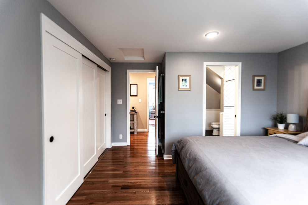 Modelo de dormitorio principal clásico renovado de tamaño medio con paredes grises, suelo de madera en tonos medios y suelo marrón