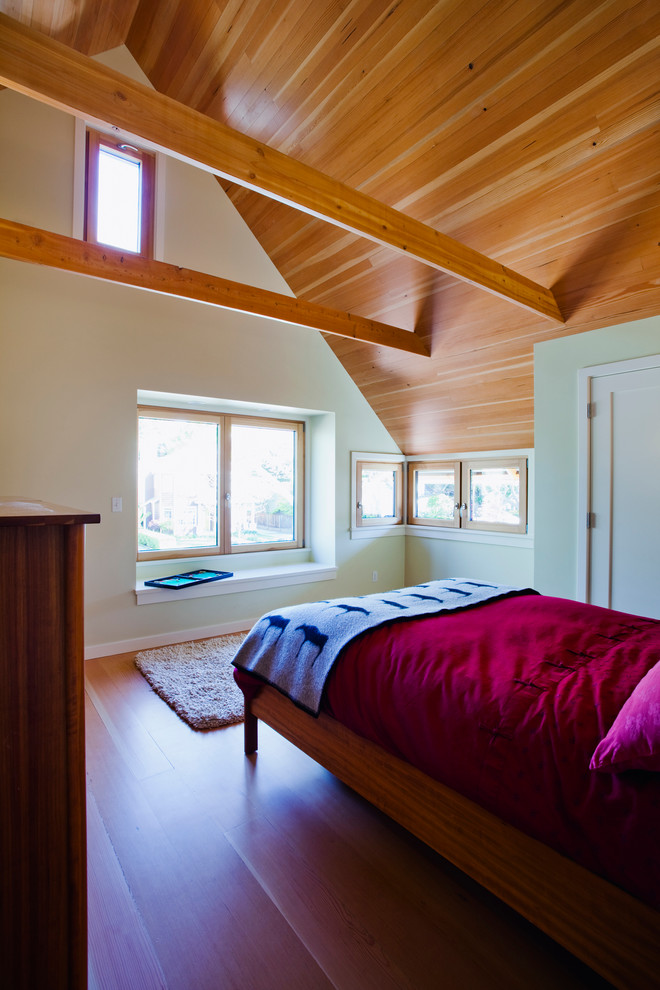 Modelo de dormitorio principal actual de tamaño medio con paredes verdes y suelo de madera clara