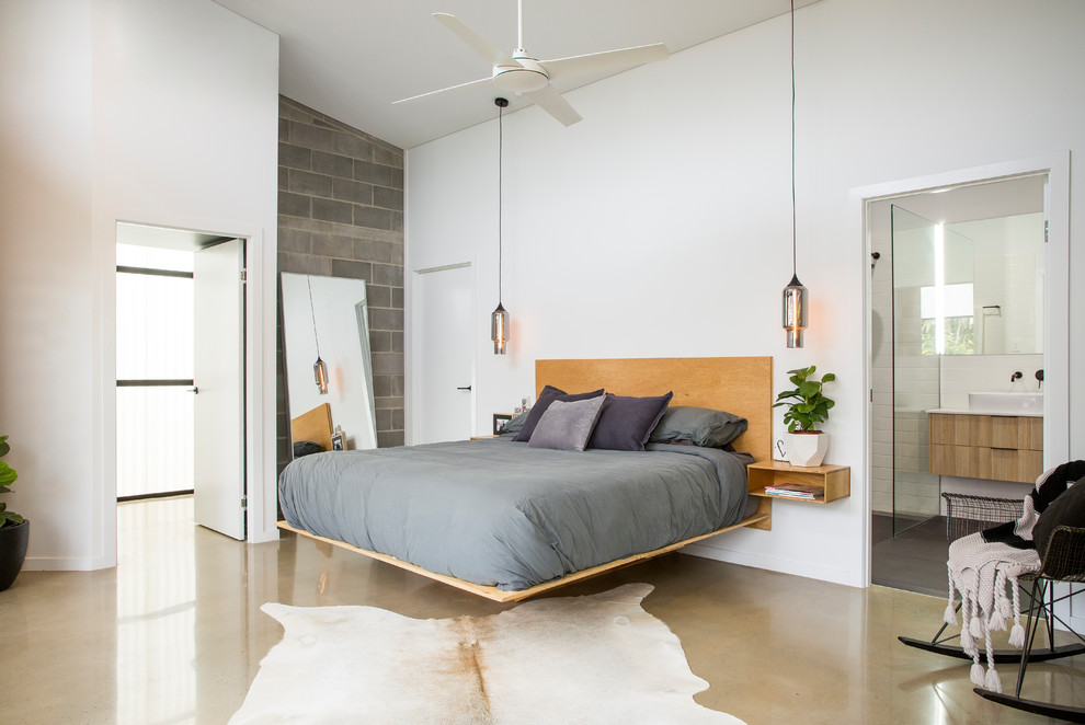 На фото: хозяйская спальня в современном стиле с белыми стенами и бетонным полом без камина с