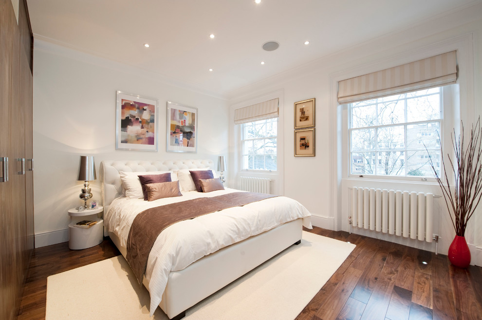 Inspiration for a large modern master bedroom in London with white walls and dark hardwood flooring.