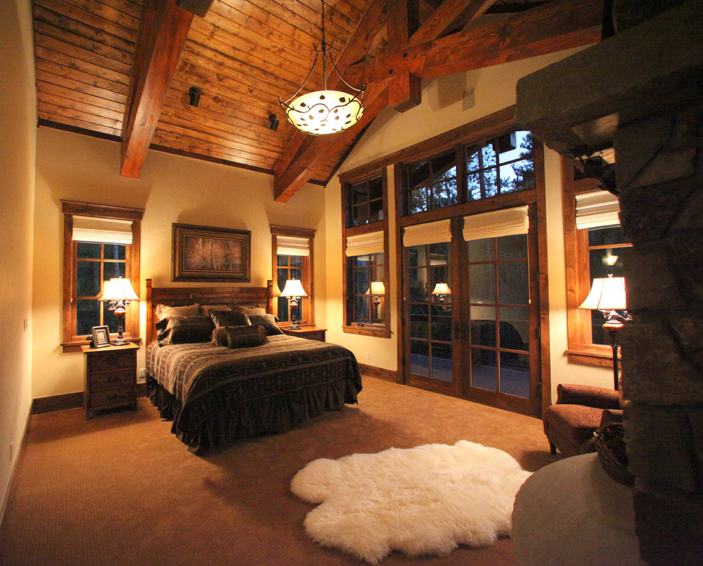 Идея дизайна: большая гостевая спальня (комната для гостей) в стиле рустика с бежевыми стенами, ковровым покрытием, стандартным камином и фасадом камина из камня