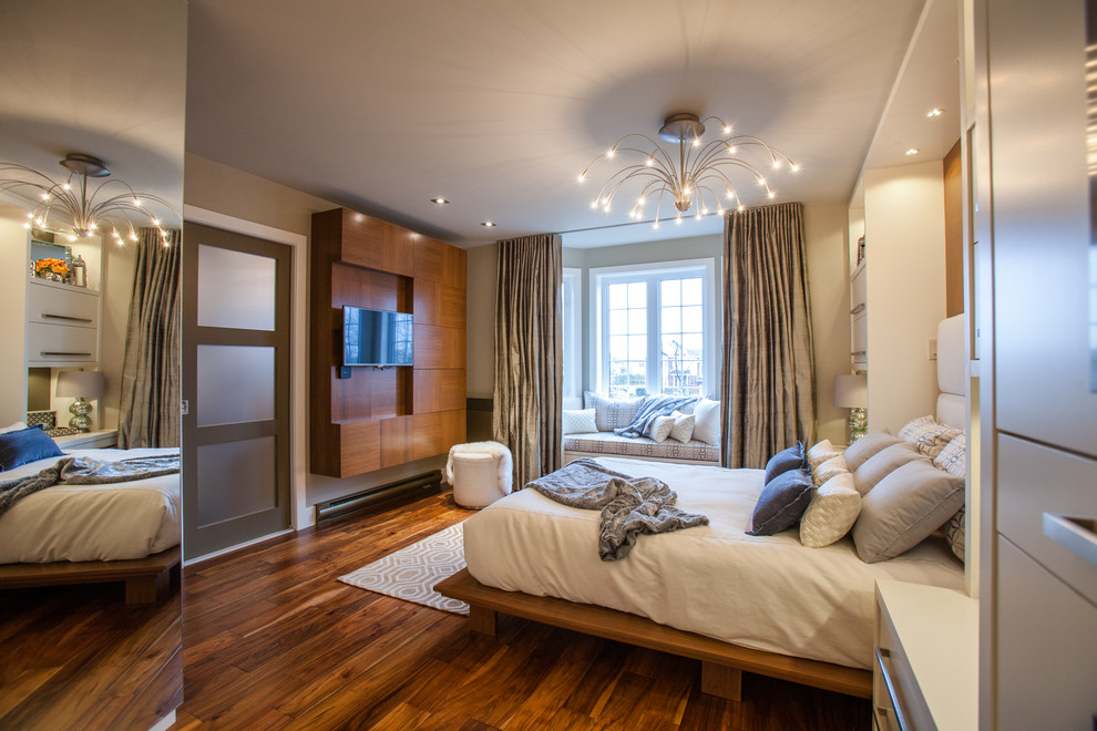 This is an example of a large modern master bedroom in Montreal with beige walls, medium hardwood flooring and no fireplace.