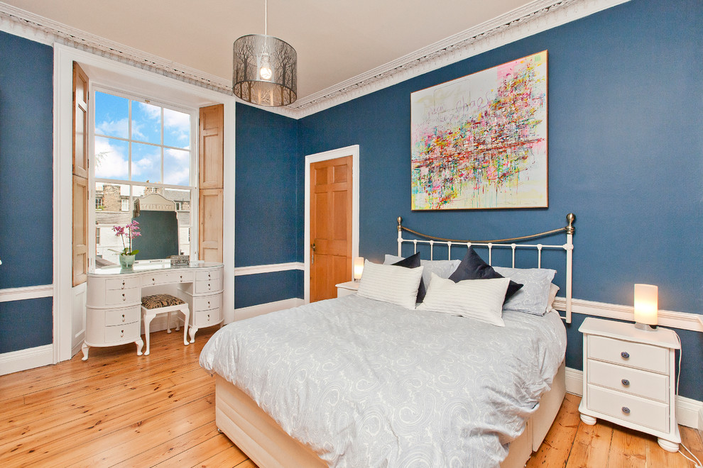 Ejemplo de dormitorio clásico de tamaño medio con paredes azules y suelo de madera clara
