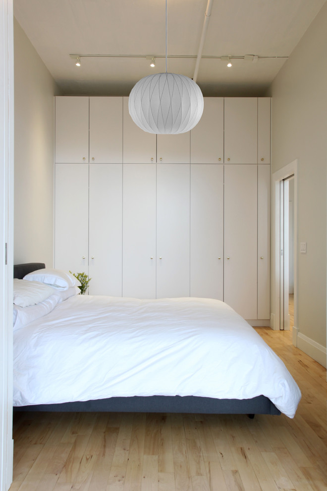 Small minimalist light wood floor bedroom photo in New York with white walls