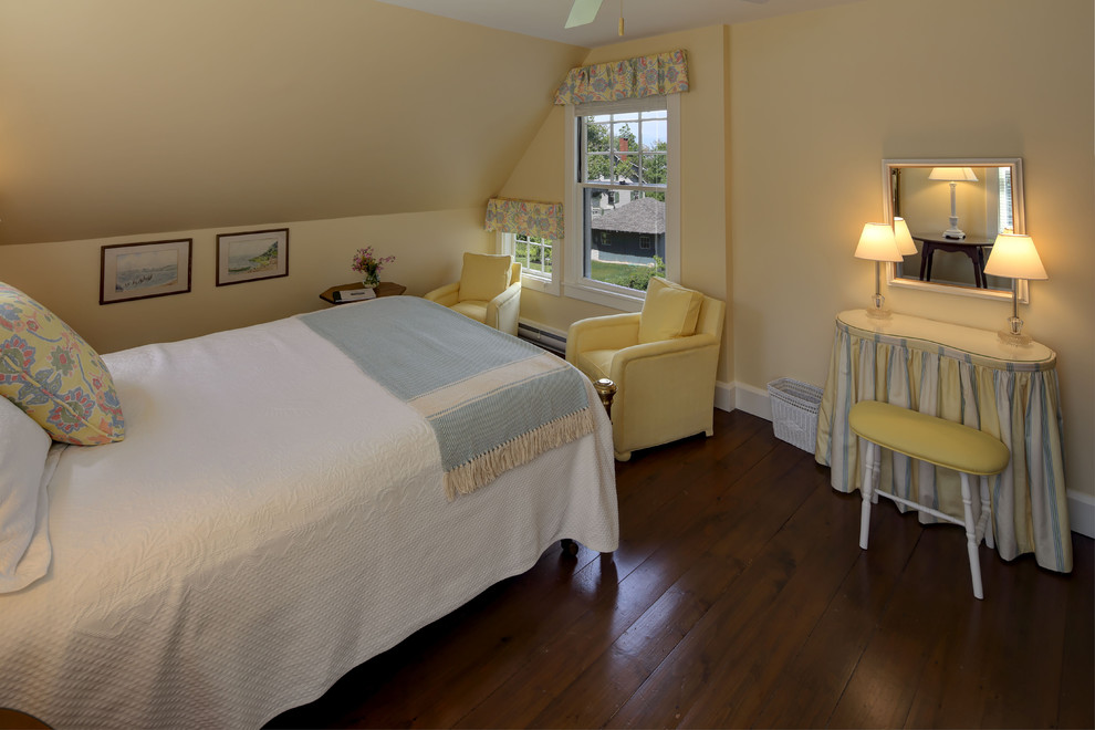 This is an example of a medium sized classic guest bedroom in Portland Maine with yellow walls, dark hardwood flooring and no fireplace.