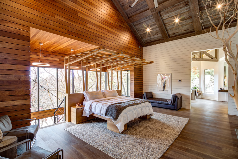 Idée de décoration pour une chambre parentale design avec un mur blanc, parquet foncé et un sol marron.