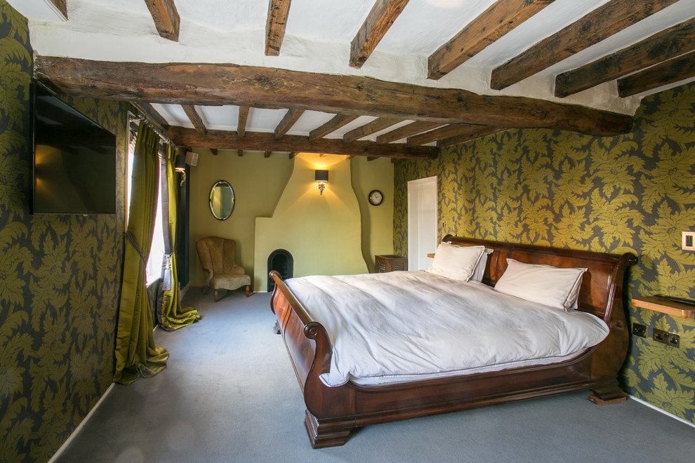 На фото: большая хозяйская спальня в стиле кантри с зелеными стенами, ковровым покрытием и стандартным камином