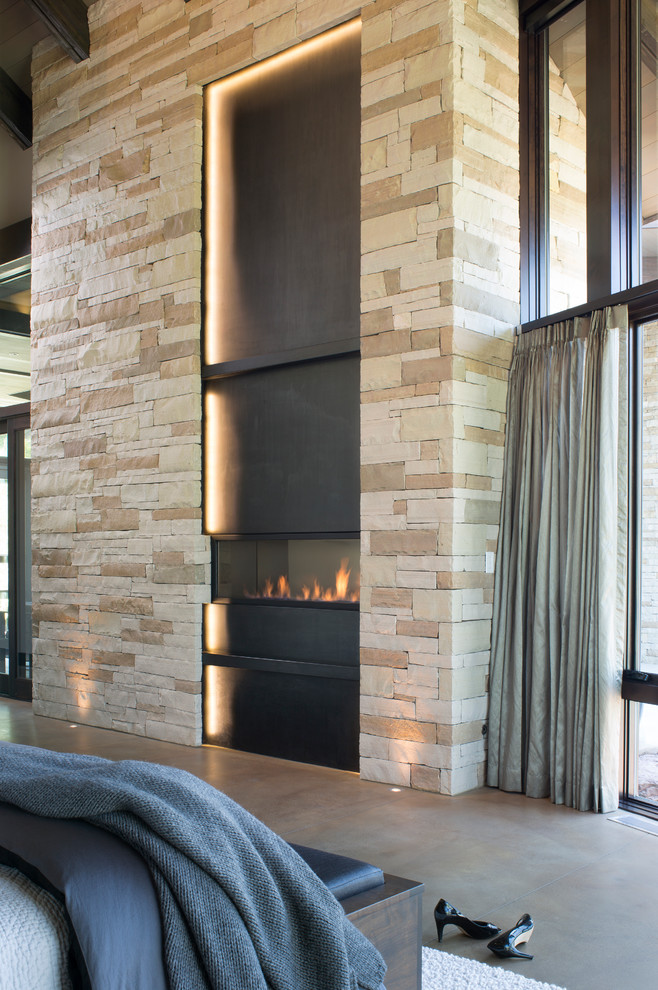 Inspiration for a medium sized contemporary master bedroom in Denver with beige walls, concrete flooring, a ribbon fireplace and a metal fireplace surround.