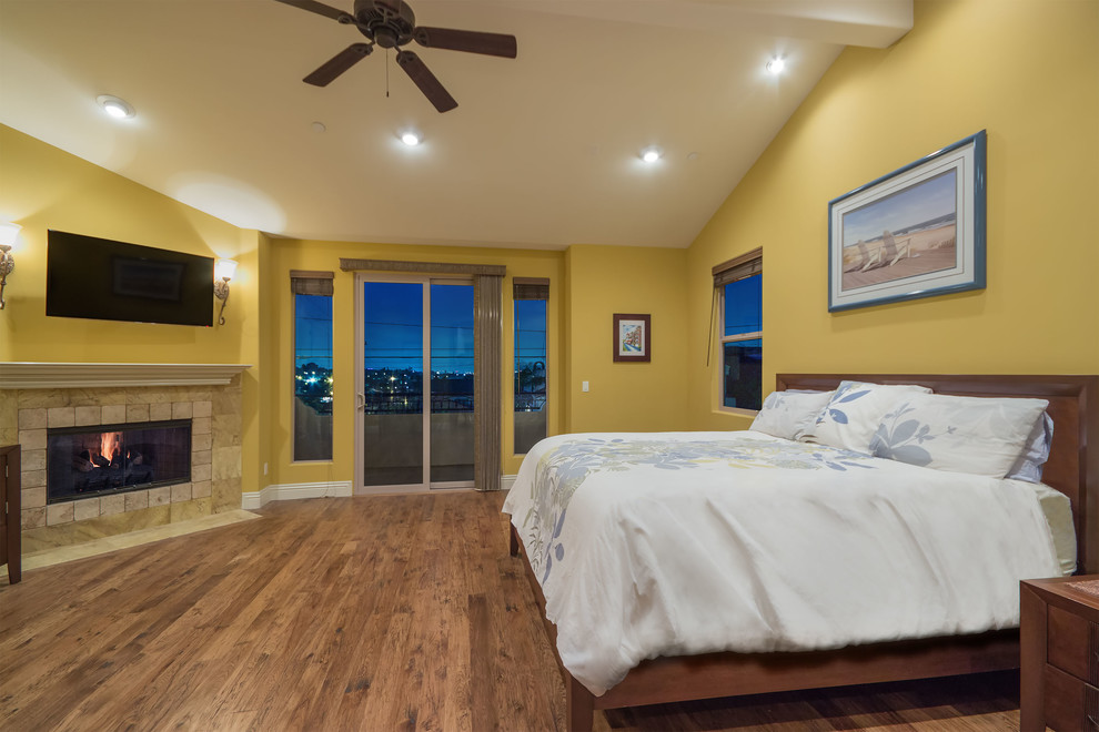 ロサンゼルスにある中くらいな地中海スタイルのおしゃれな主寝室 (黄色い壁、無垢フローリング、標準型暖炉、石材の暖炉まわり) のインテリア