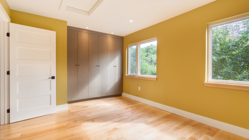 他の地域にある中くらいなコンテンポラリースタイルのおしゃれな客用寝室 (黄色い壁、淡色無垢フローリング) のインテリア
