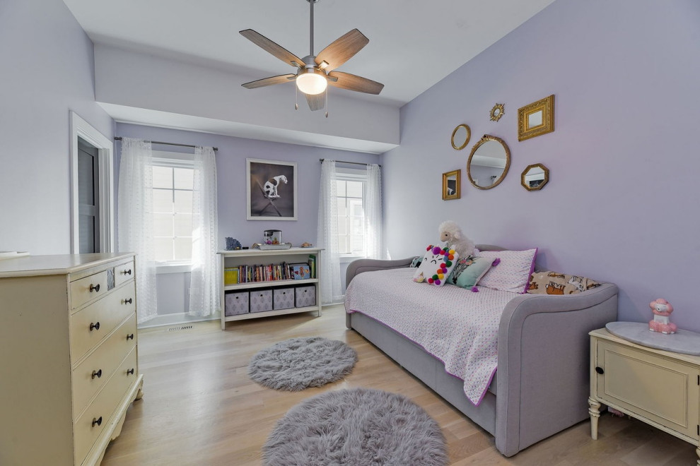 Modelo de habitación de invitados clásica renovada de tamaño medio con paredes púrpuras, suelo de madera clara y suelo marrón