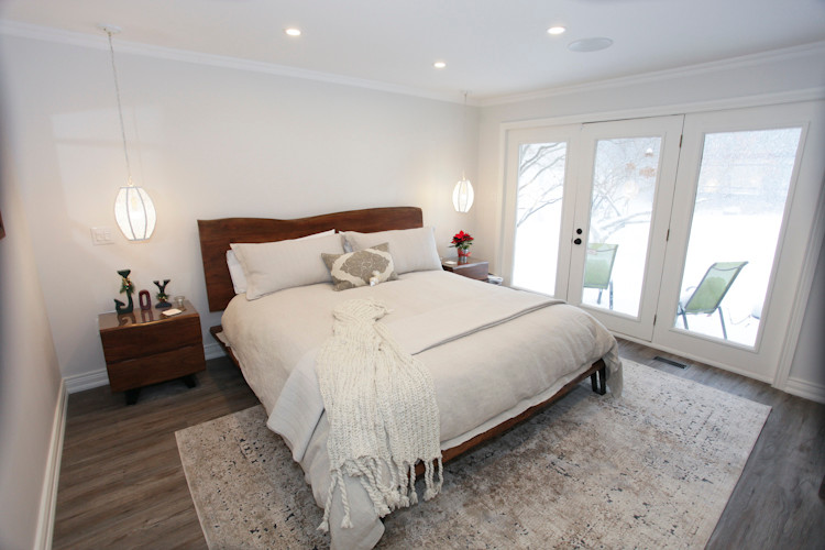 Mittelgroßes Landhausstil Hauptschlafzimmer mit weißer Wandfarbe und braunem Holzboden in Toronto