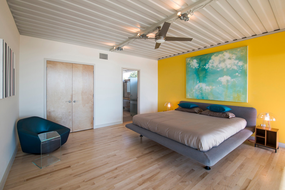 Diseño de dormitorio actual con paredes amarillas y suelo de madera clara