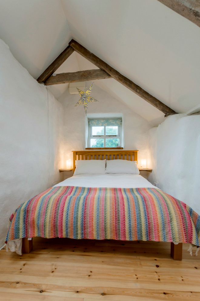 Cette image montre une petite chambre d'amis rustique avec un mur blanc et parquet clair.