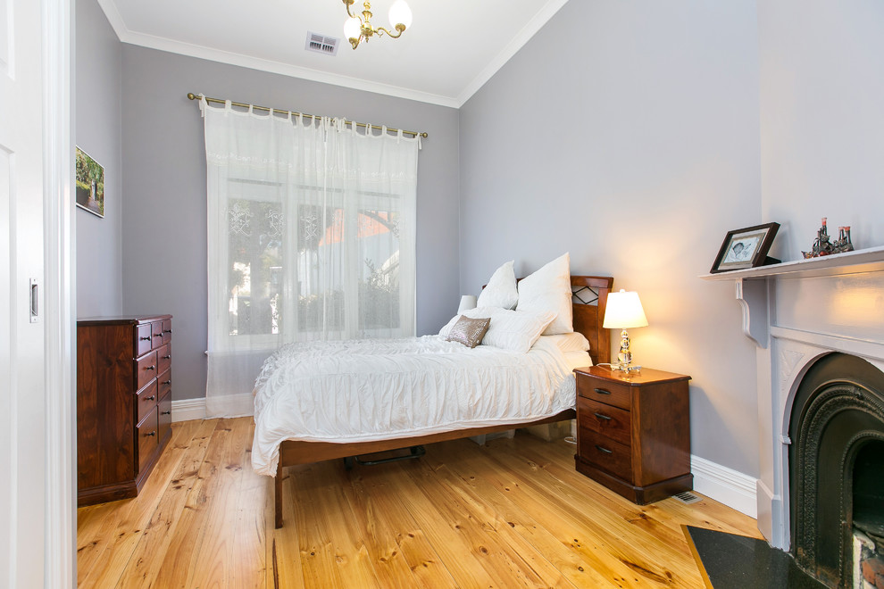 Shabby-Chic Hauptschlafzimmer mit grauer Wandfarbe, hellem Holzboden, Kamin und Kaminumrandung aus Metall in Melbourne
