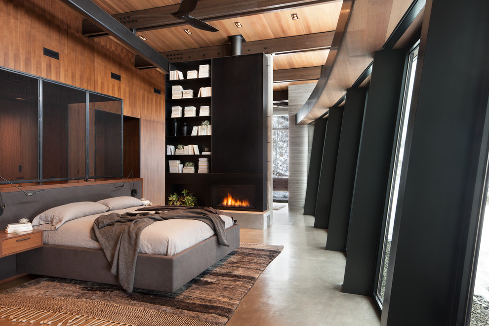 Идея дизайна: большая хозяйская спальня в современном стиле с бетонным полом, горизонтальным камином, фасадом камина из металла, серым полом и коричневыми стенами