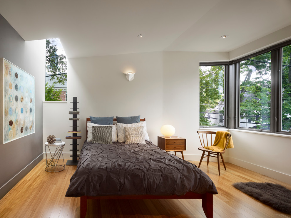 Photo of a modern bedroom in New York with white walls, medium hardwood flooring and yellow floors.