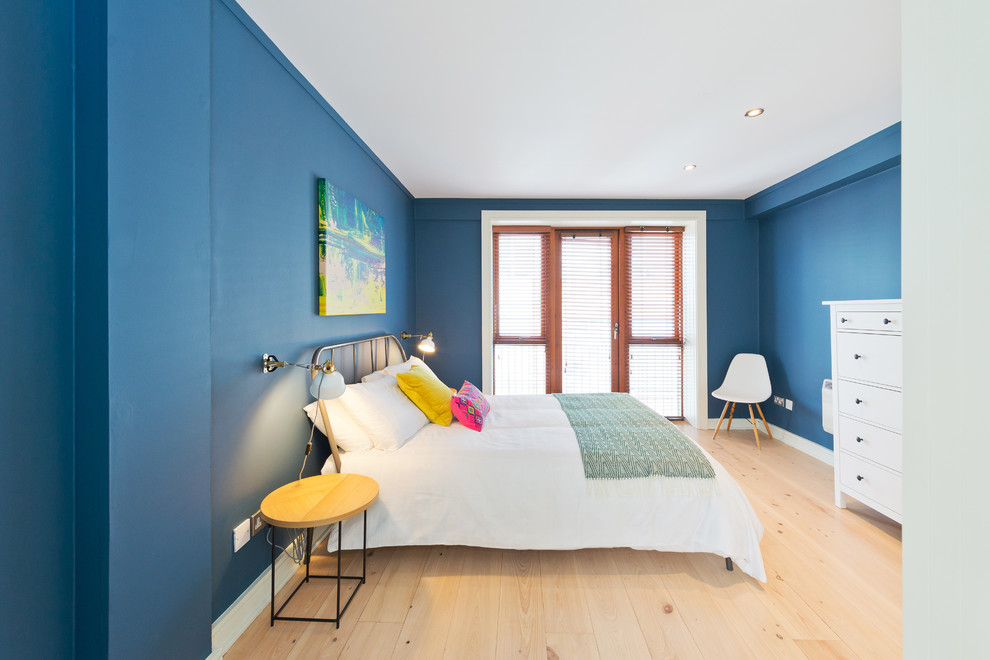 Ispirazione per una camera da letto design di medie dimensioni con pareti blu, parquet chiaro e nessun camino
