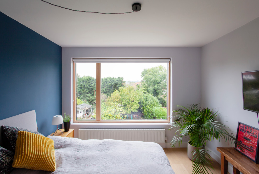 Idéer för ett mellanstort modernt sovloft, med blå väggar och ljust trägolv