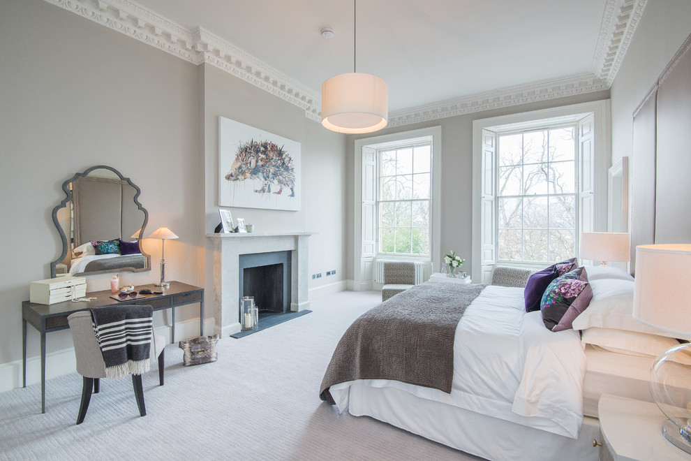 Photo of a large master bedroom in Glasgow with beige walls, carpet, a standard fireplace and a stone fireplace surround.