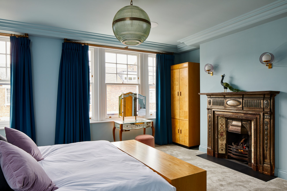 This is an example of a traditional bedroom in London with blue walls, carpet, a standard fireplace and grey floors.