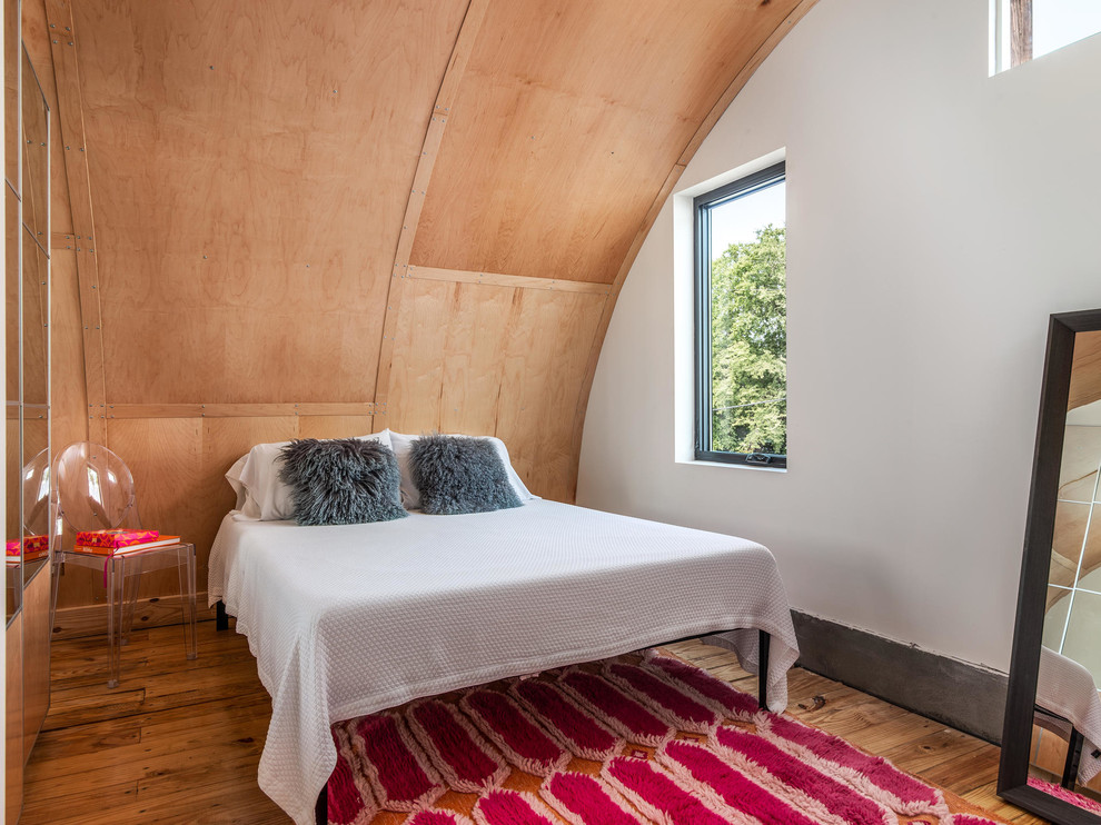 Imagen de dormitorio principal urbano pequeño con suelo de madera clara