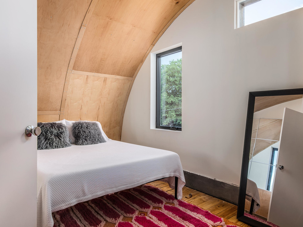 Diseño de dormitorio principal urbano pequeño con suelo de madera clara