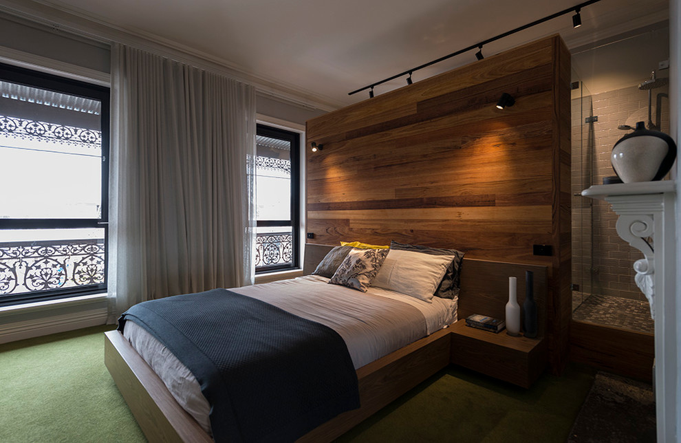 Aménagement d'une grande chambre moderne avec un mur gris, un sol vert, une cheminée standard et un manteau de cheminée en plâtre.