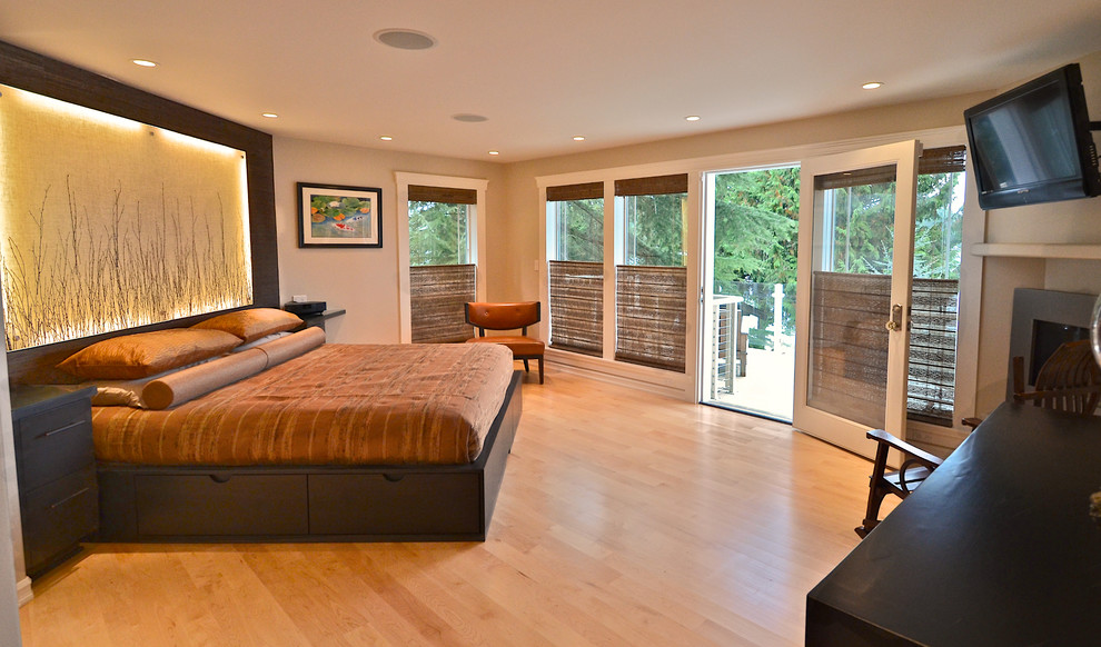 Modelo de dormitorio principal contemporáneo grande con paredes beige, suelo de madera clara, chimenea de esquina y marco de chimenea de metal