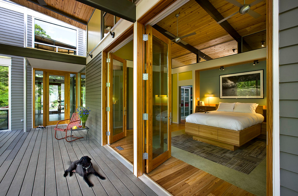 Aménagement d'une grande chambre parentale contemporaine avec un mur vert, un sol en bois brun, aucune cheminée et un sol marron.