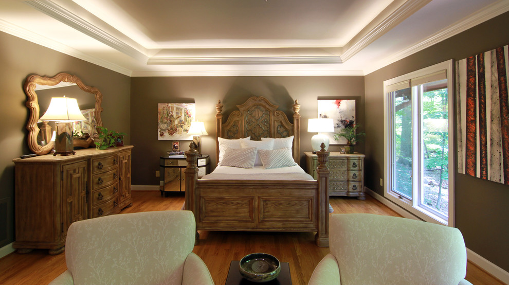 Modelo de dormitorio principal clásico renovado de tamaño medio con paredes grises, suelo de madera en tonos medios, todas las chimeneas y marco de chimenea de piedra
