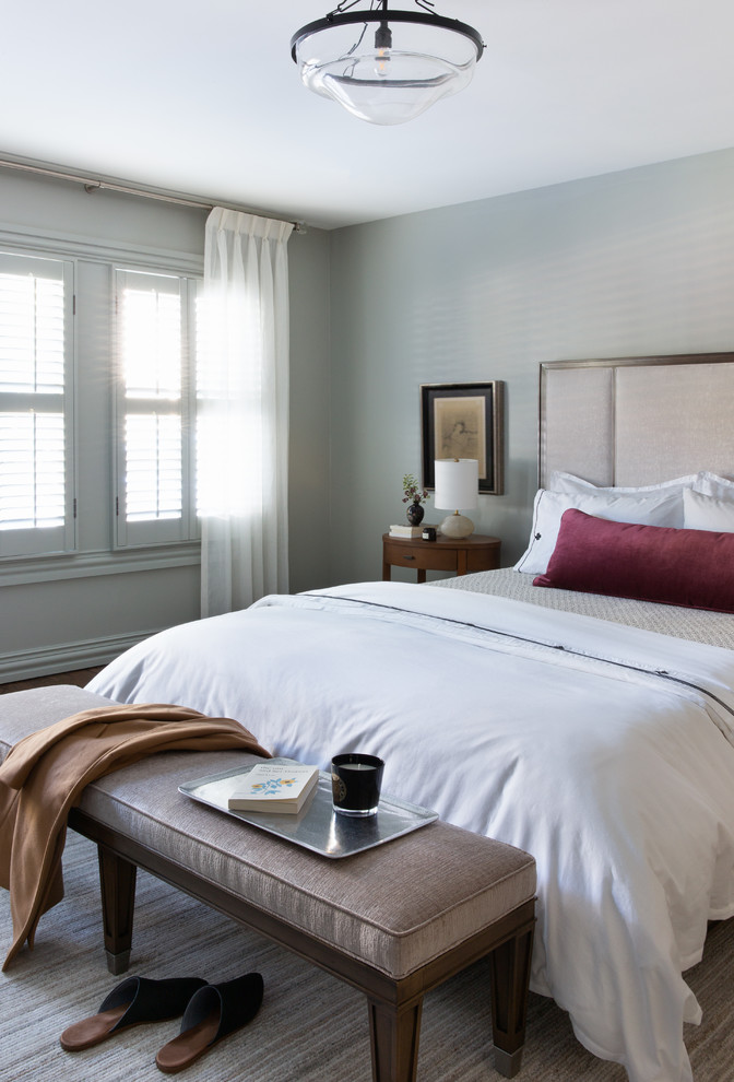 Modelo de dormitorio principal clásico renovado de tamaño medio con paredes azules y suelo de madera clara