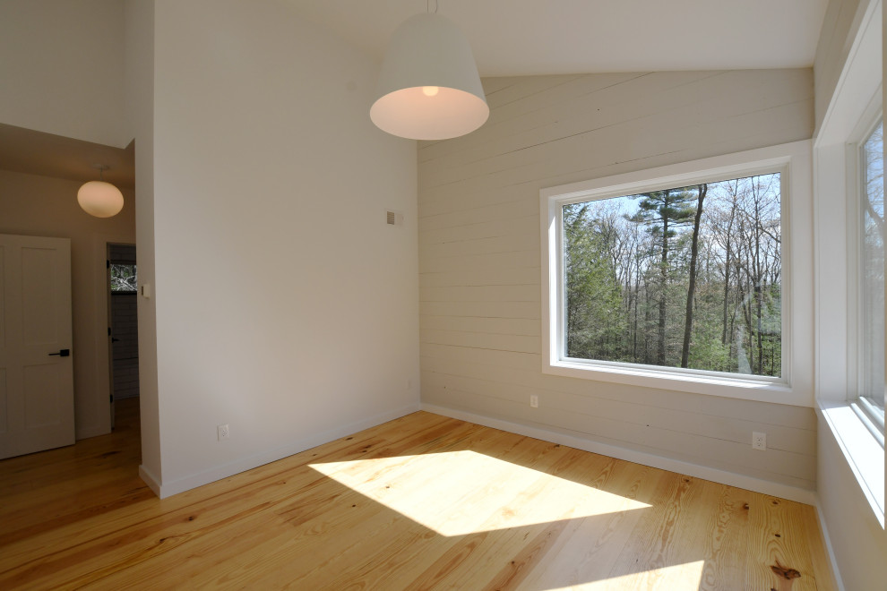 Inspiration for a mid-sized 1960s master light wood floor, brown floor, vaulted ceiling and shiplap wall bedroom remodel in New York with gray walls