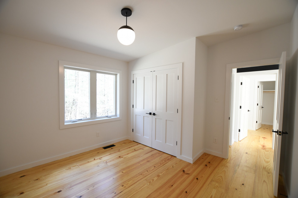 Ejemplo de habitación de invitados retro de tamaño medio con paredes blancas, suelo de madera clara y suelo marrón