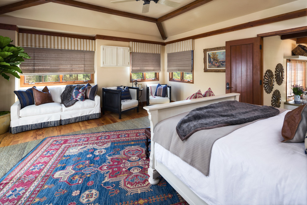 Immagine di una camera matrimoniale american style di medie dimensioni con pareti beige, pavimento in legno massello medio e nessun camino