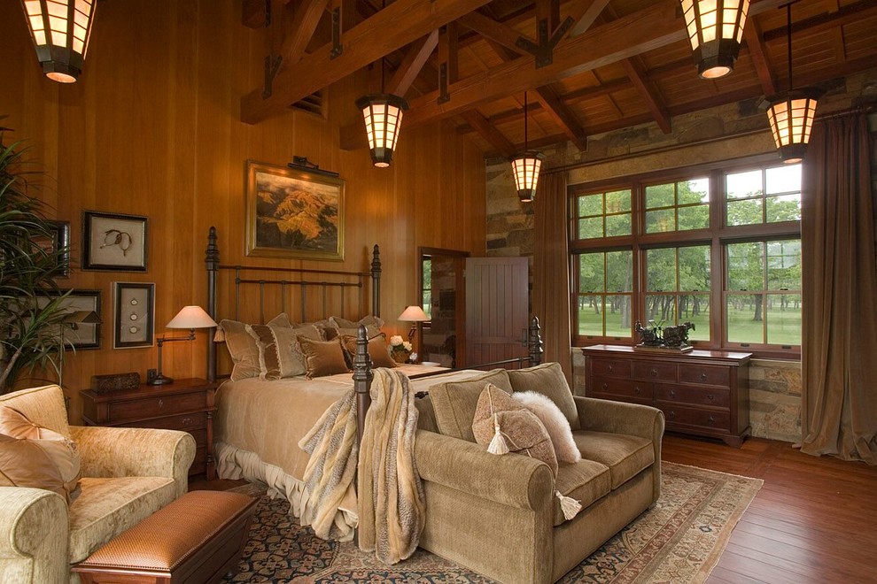 Mittelgroßes Country Hauptschlafzimmer mit beiger Wandfarbe, braunem Holzboden, Kamin, Kaminumrandung aus Stein und beigem Boden in Austin