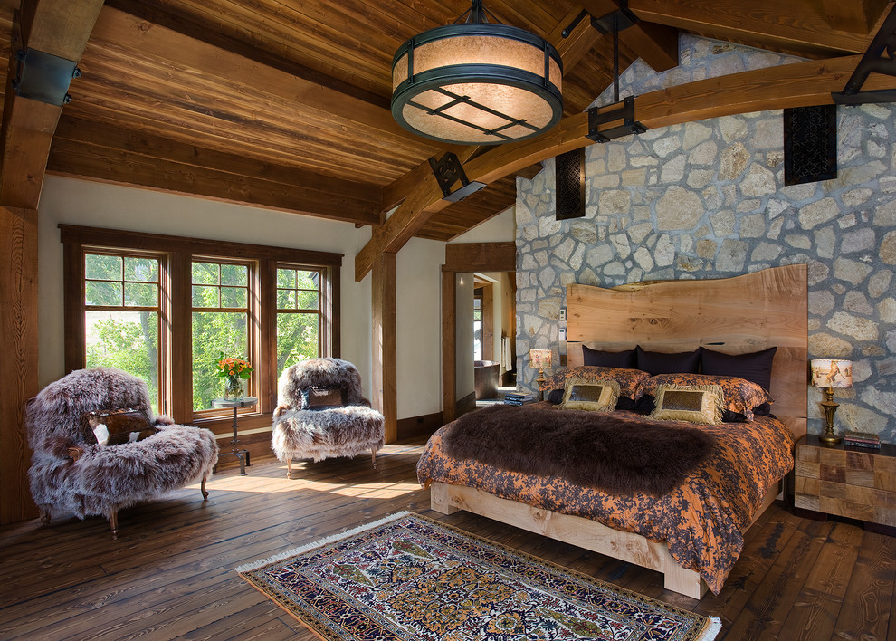 Modelo de dormitorio principal rural grande con paredes beige y suelo de madera oscura