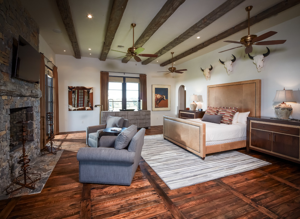 Rustikales Schlafzimmer mit weißer Wandfarbe, braunem Holzboden, Kamin und Kaminumrandung aus Stein in Houston