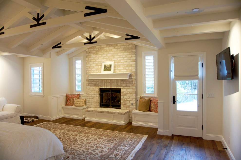Idée de décoration pour une chambre parentale champêtre avec un mur beige, parquet foncé, une cheminée standard et un manteau de cheminée en brique.