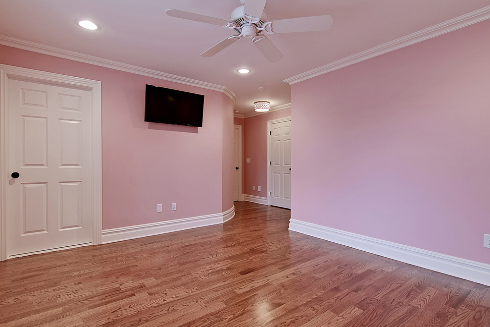 Cette image montre une chambre d'amis traditionnelle de taille moyenne avec un mur rose, un sol en bois brun, aucune cheminée et un sol marron.