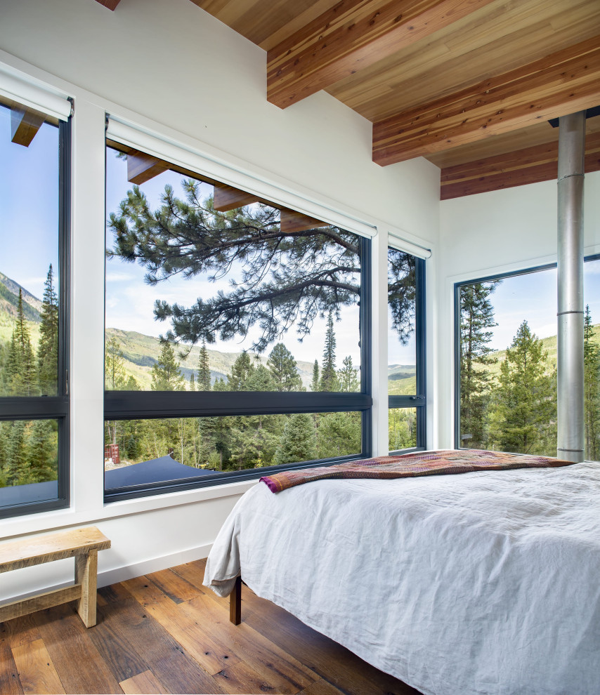 Modernes Schlafzimmer mit weißer Wandfarbe, dunklem Holzboden, braunem Boden, freigelegten Dachbalken und Holzdecke in Denver