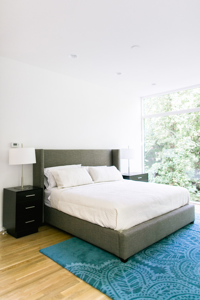 Inspiration for a contemporary bedroom in Raleigh with white walls and medium hardwood flooring.