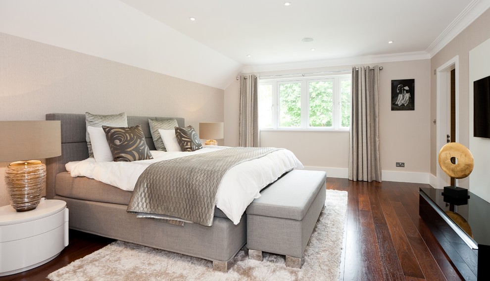 This is an example of a medium sized contemporary master bedroom in London with beige walls and dark hardwood flooring.