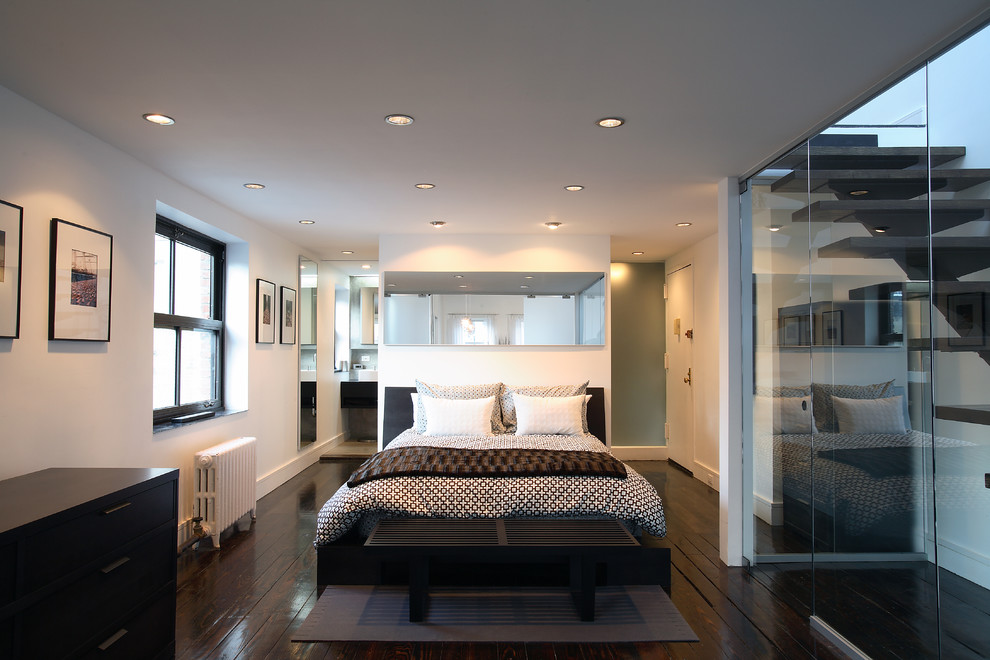 Großes Modernes Hauptschlafzimmer ohne Kamin mit weißer Wandfarbe, dunklem Holzboden und braunem Boden in New York