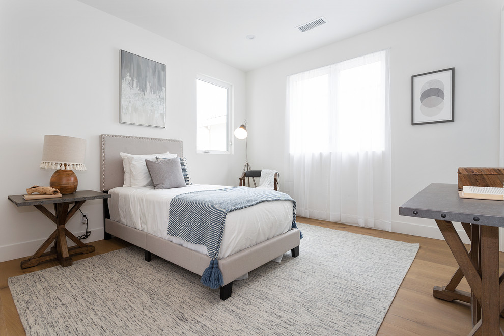 Transitional guest medium tone wood floor and brown floor bedroom photo in Los Angeles with white walls