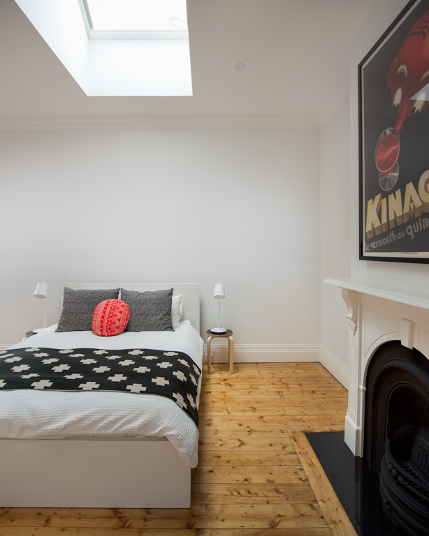 Cette image montre une chambre d'amis urbaine de taille moyenne avec un mur blanc, parquet clair, une cheminée standard et un manteau de cheminée en métal.